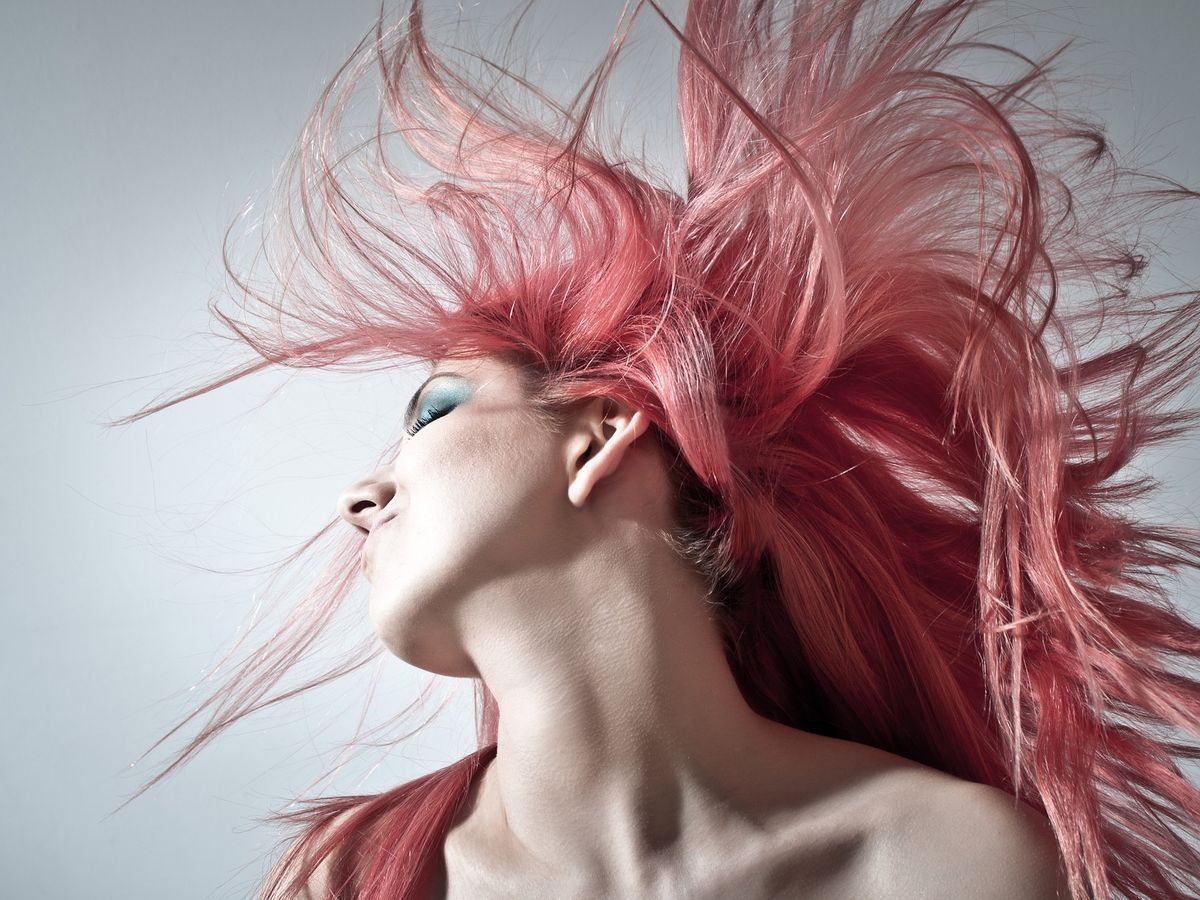 A woman flicking bright pink coloured hair